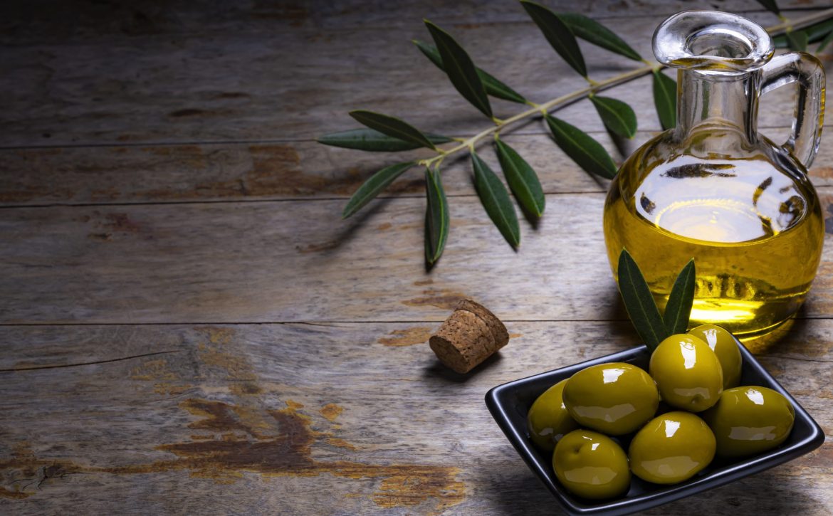 Tasty looking olives extra virgin olive oil and olive leafs on dark wooden background